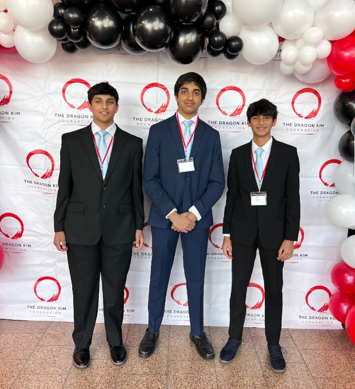 Three teen founders of Life Savers Phoenix standing in front of a Dragon Kim Foundation backdrop with black, white, and red balloons